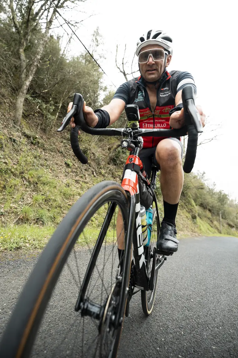 Cycliste en danseuse, vu de très près, sur une route de causse